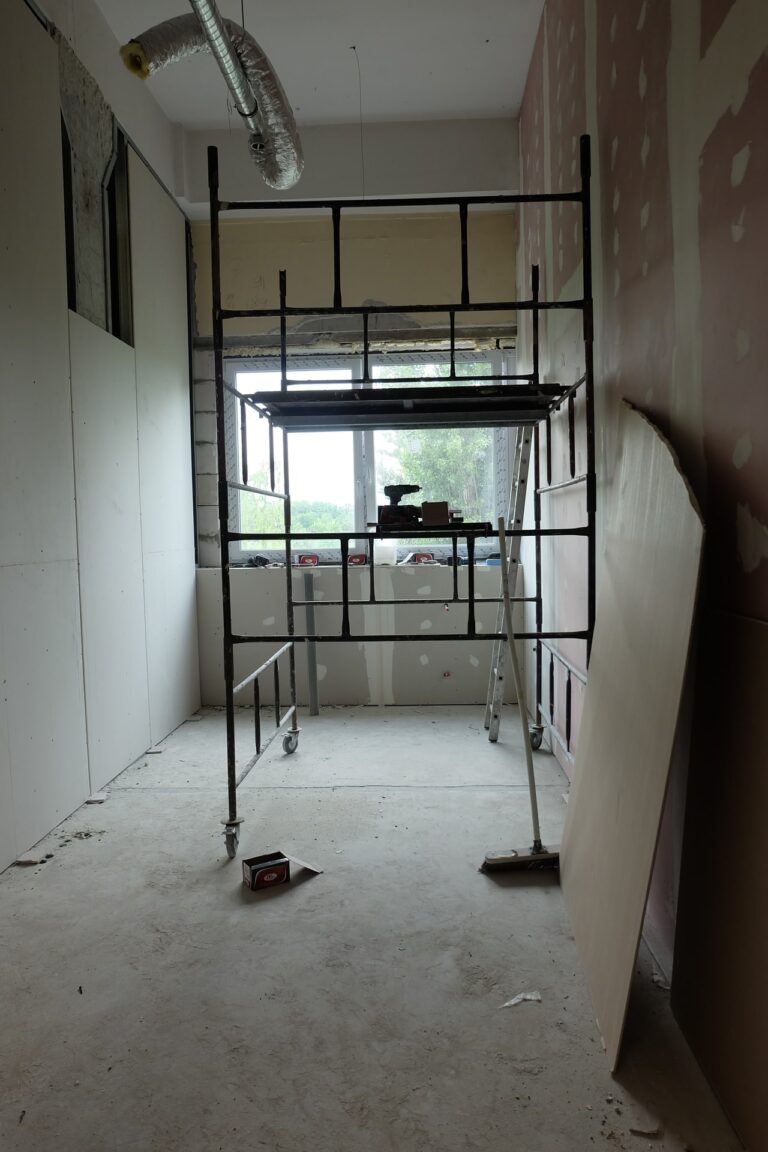 Na zdjęciu widac pokój w remoncie na środku znajduje się rusztowanie o ściane oparta jest płyta na końcu pokoju jest okno