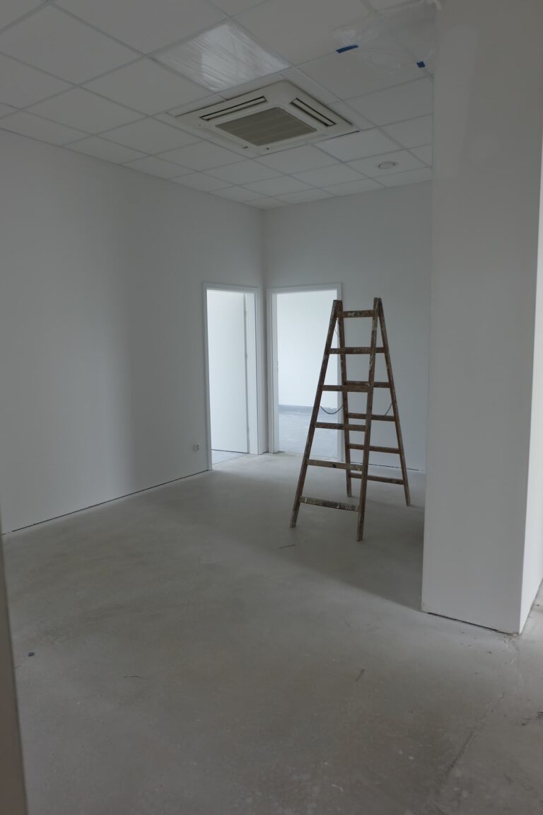 Na zdjęciu znajduje się wnętrze jednego z gabinetów. Pokój jest w remoncie, ma białe ściany. Na środku jest rozstawiona drabina.