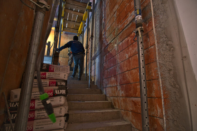 Na zdjęciu widać klatkę schodową w czasie remontu na schodach widać 2 osoby.