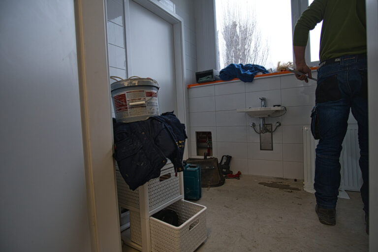 Na zdjęciu widać łazienkę w czasie remontu. po prawej stronie widać pana robotnika od tyłu